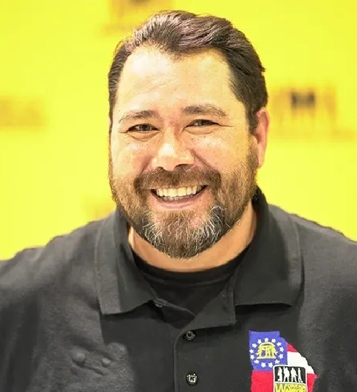 A man with a beard and mustache wearing a black shirt.